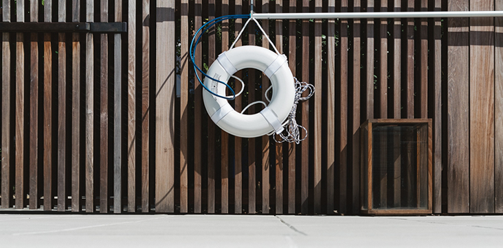 stock photo of lifesaver hanging on fence by pool